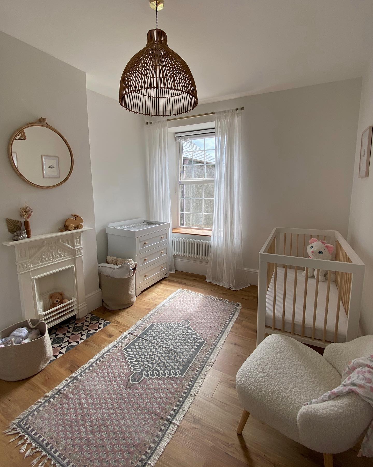 A cozy and well-lit nursery room with a crib, comfortable chair, decorative rug, and elegant decor.