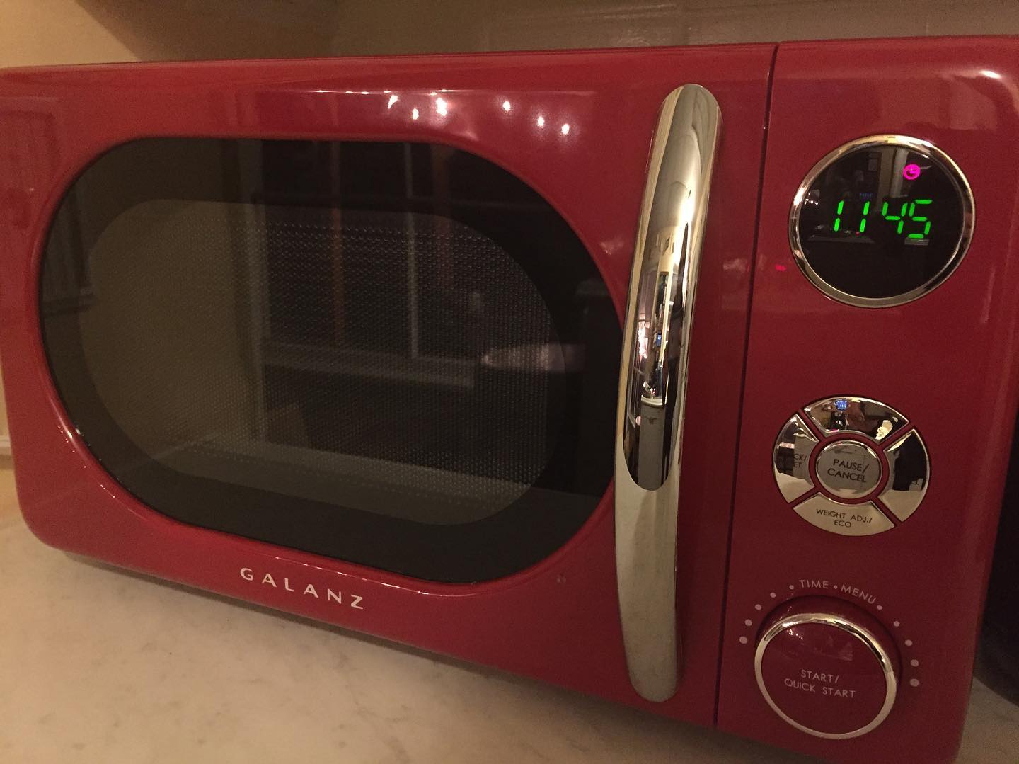 A red Galanz microwave with a retro design, featuring chrome accents, rotary dials, and a digital clock reading 11:45.