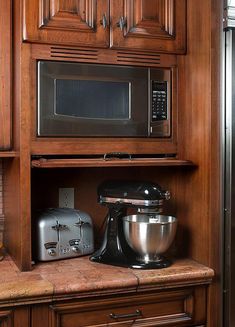 A built-in microwave oven installed above a countertop with a toaster and a stand mixer.