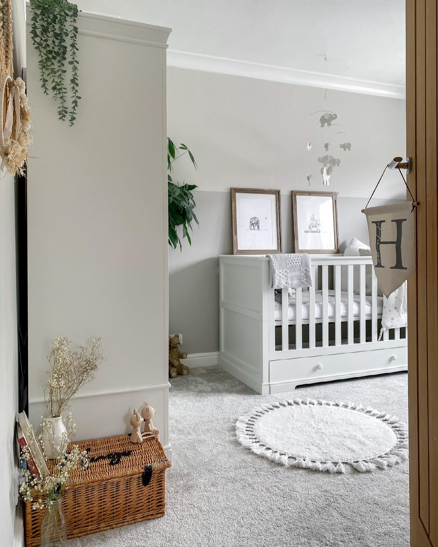 A peaceful and well-organized nursery room with a white crib, framed artwork, and decorative elements that create a calming atmosphere.