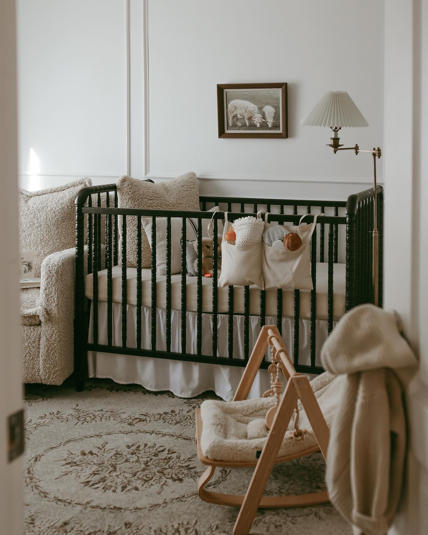 A serene and cozy baby’s room featuring a dark green crib adorned with plush pillows, a comfy rocking chair, and warm lighting creating a peaceful atmosphere.