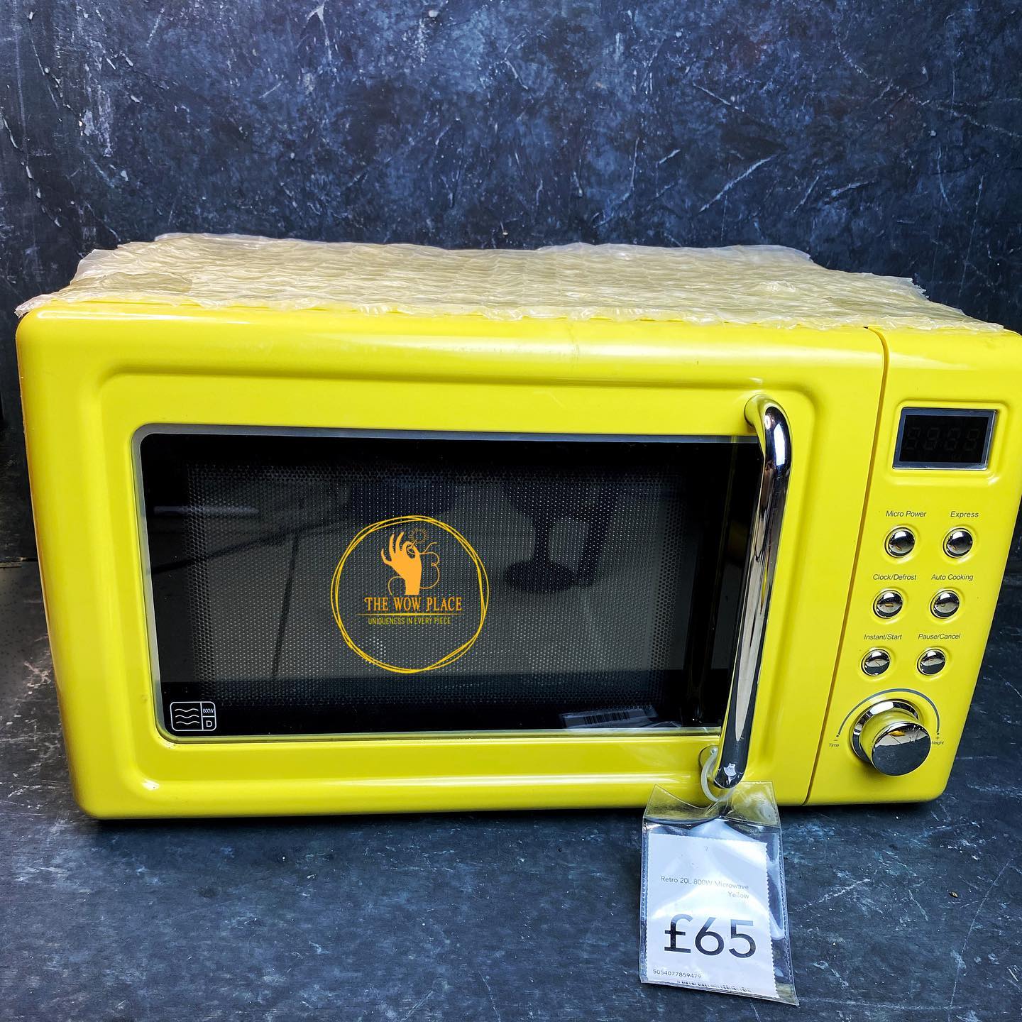 A bright yellow retro-style microwave with a digital screen and a price tag of £65.