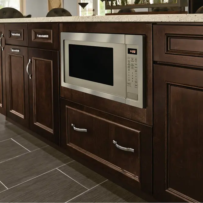 A built-in microwave oven integrated into dark wooden cabinetry in a modern kitchen setting. 