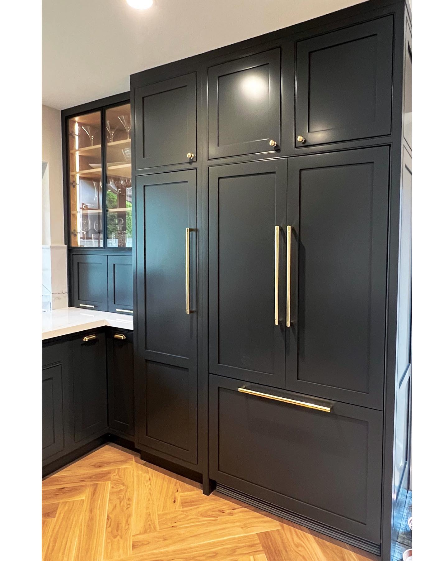 A panel-ready refrigerator with dark panels, seamlessly blending with the cabinetry in a modern kitchen.